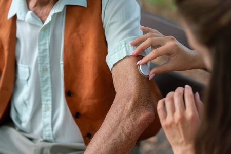 Caregiver helping senior diabetic man to apply continuous glucose monitor sensor on his arm.