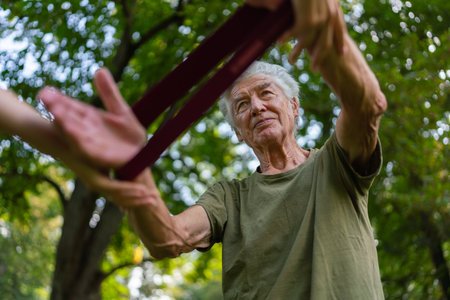 The senior man exercising in the park, using resistance band.の写真素材