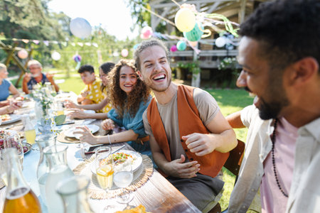 Friends chatting, laughing, and having fun at party table during summer garden party. Men best friends,friendship between males, bromance.の写真素材
