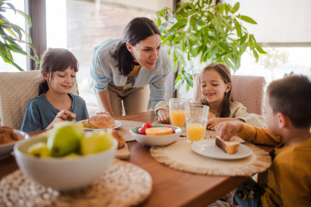 Mother prepares breakfast for children, in the morning. Maternal love and care for household and family.の写真素材
