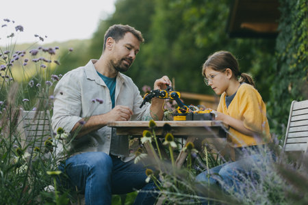 Father supporting daughter in pursuing robotics, science, IT technologies and programming. Young...