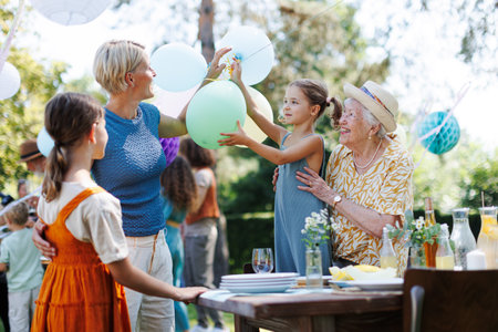 Grandmother, mother and daughters setting decorations for summer garden party. Three generations of...
