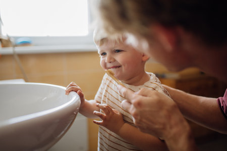 Father brushing little baby boys teeth in the morning. Morning dental hygiene for toddlers.