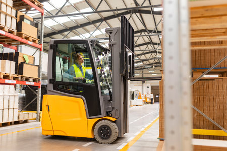 Female warehouse worker driving forklift. Warehouse worker preparing products for shipmennt, delivery, checking stock in warehouse.の写真素材