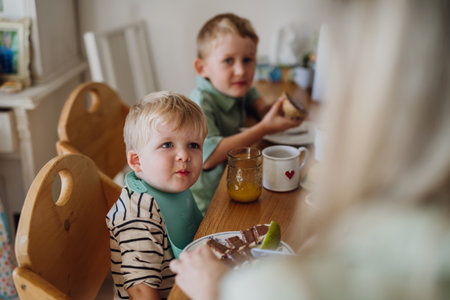 Family eating breakfast together in home kitchen. Healthy breakfast or snack before preschool,...