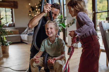 Father and vacuuming sons hair with vacuum cleaner. Father with kids cleaning house, helping with...