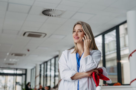 Portrait of beautiful female doctor with christmas hat in hand phone calling. Working in hospital on Christmas day, Christmas Eve. Female doctor working a Christmas shift and cant be with her family.の写真素材