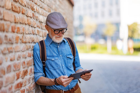 Senior tourist exploring new city, interesting places. Elderly man holding tablet and looking for the route. Traveling and solo trips in retirement.の写真素材