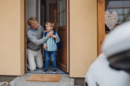 Boy getting ready for school, putting on shoes, getting dressed. Father taking son to school, kindergarten before going to work.の写真素材