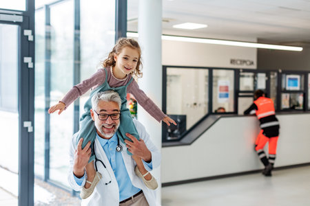 Portrait of a pediatrician with a little patient sitting on his shoulders, piggyback. Friendly relationship between the doctor and the child patient.の写真素材