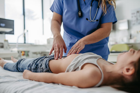Doctor palpating girls abdomen, using hands and steady pressure. Concept of preventive health care...
