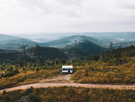 Aerial view of small camper trailer in the middle of summer forest, with campers sitting by fire.の写真素材
