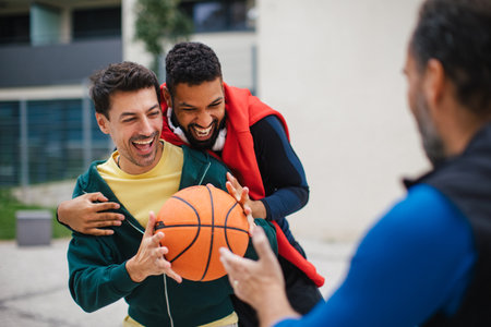 Best friends playing sport outdoors, having fun, competing. Playing basketball at a local court, enjoying exercise together. Concept of male friendship, bromance.の写真素材
