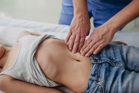 Close up of doctor palpating girls abdomen, hands and steady pressure on belly. Concept of preventive health care for children.の写真素材