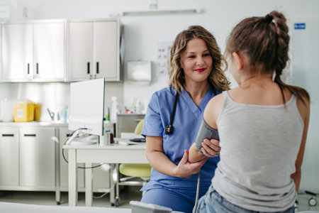 Doctor examining young girl, measuring blood pressure, using medical blood pressure monitor. Concept of preventive health care for children.の写真素材