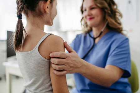 Orthopedist examines the spine, posture, and spinal deformities of little girl. Girl visiting paediatrician for annual preventive exam. Concept of preventive health care for children.の写真素材