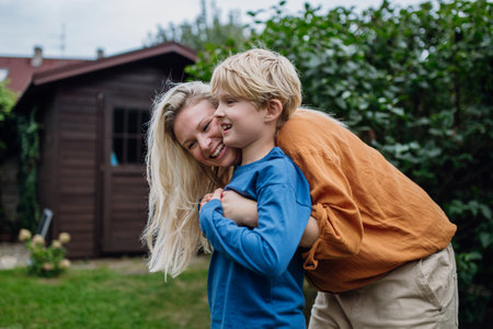 Mother hugging son from behind, bonding moment. Real family, real people. Concept of Mothers Day,...