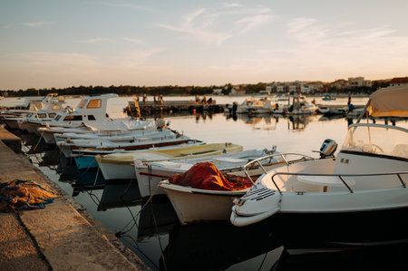 Small boats on calm water, moored in the harbor during sunset.