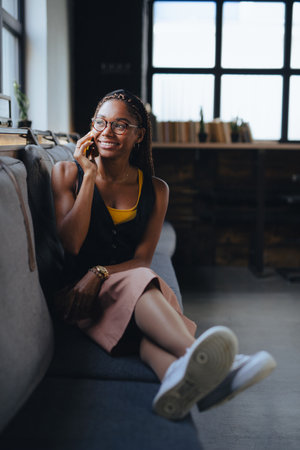 Portrait of beautiful woman sitting in modern office and making phone call, smiling. Working...