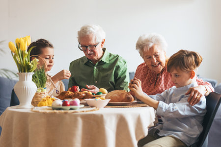 Grandparents with grandchildren eating traditional easter lunch. Recreating family traditions and customs. Happy easter.の写真素材