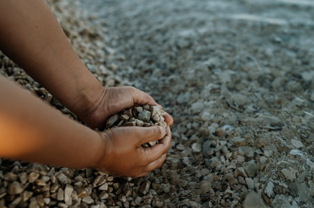 Close up of sea pebbles in boys palms, pruney fingers. Seraching for shells in the sand. Concept of summer vacation by sea.の写真素材