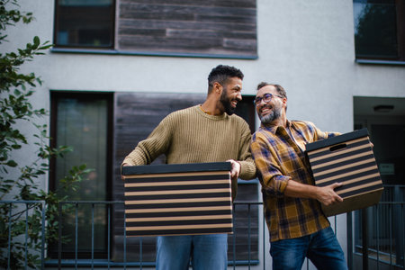 Man helping his friend move into new apartment in building. Man is moving into new flat, carrying...