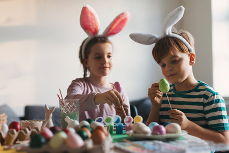 Young kids decorating easter eggs at home. Tradition of painting eggs with brush and easter egg dye.の写真素材