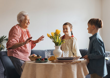 Grandmother with grandchildren setting table for traditional easter lunch. Recreating family traditions and customs.の写真素材