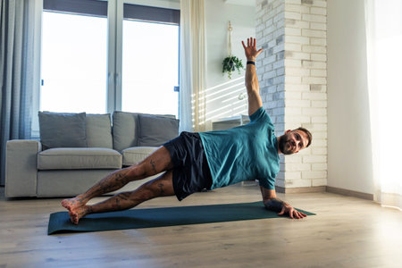 Handsome man doing yoga, stretching, resting after home workout, New Years resolutions, exercising...