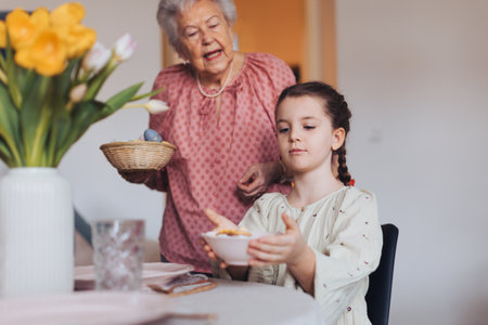 Grandmother with granddaughter setting table for traditional easter lunch. Recreating family traditions and customs.の写真素材