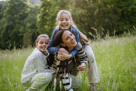 Beautiful mother with two daughters, embracing at meadow. Concept of Mothers Day, maternal love.