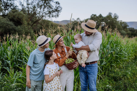 Farmer family standign in front of field with corn. Concept of multigenerational and family farming.
