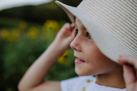 Beautiful young girl standing in front of sunflowers on field. Girl enjoying a beautiful flowers in the summer farm fields. Future female farmer.の写真素材