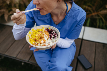 Nurse having healthy lunch in front of hospital building, taking break from work. Importance of breaks in healthcare.の写真素材