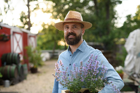 Portrait of farmer holding lavender plant in pot, working on family farm.の写真素材