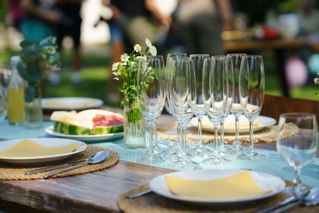 Close up shot of empty wine glasses, cutlery and utensils at summer garden party.