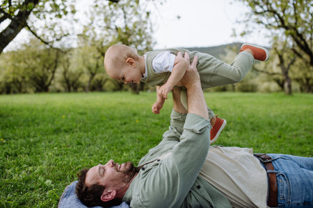 Father holding little baby, playing, having fun during warm spring day. Fathers day concept.の写真素材