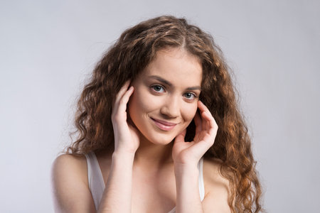 Portrait of a gorgeous teenage girl with curly hair. Studio shot, white background with copy spaceの写真素材