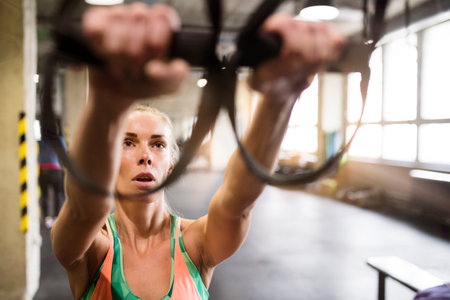 Beautiful sport woman doing suspension training, total resistance exercise. Routine workout for...