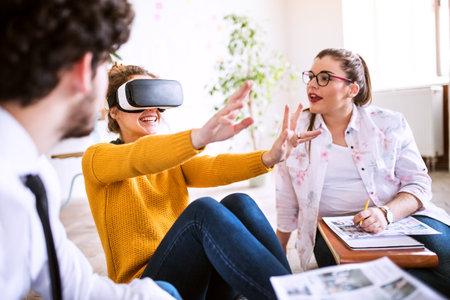 Young group of colleagues using VR technology in startup company office. Virtual reality in...