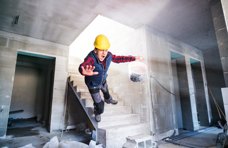 Man falling down the stairs. Accident of a man worker at the construction site. Work injury, accident in workplace.の写真素材