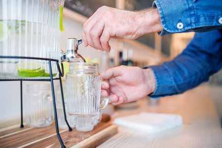 Ice cold water freshened with slices of limes in glass dispenser with spigot at the bottom.の写真素材