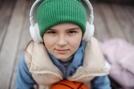 Outdoor portrait of cute young girl with beanie hat and headphones. Girl with long hair going to school.の写真素材