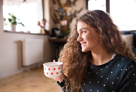 Morning routine for beautiful woman with curly hair, drinking cup of coffee.の写真素材