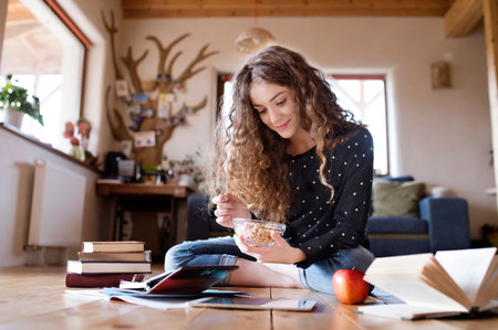 Female student sitting on floor, reading books, studying for final exam at university. Beautiful...