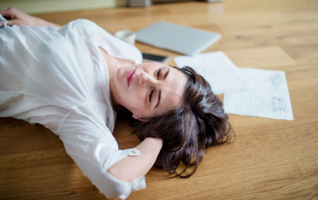 Mature woman taking break during homeoffice work. Woman paying bills online, lying on floor.