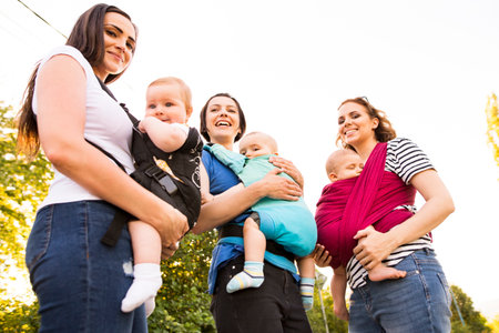 Mothers carrying babies in carriers, slings or wraps. Babywearing.の写真素材