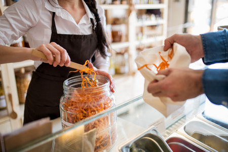 Shop assistant serving customer in package-free store using reusable containers. Zero waste shops offering package-free bulk goods and sustainable alternatives.の写真素材