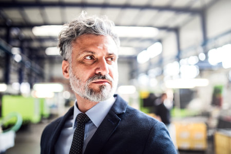 Portrait of project manager standing in modern industrial factory. Manufacturing facility with robotics, robotic arms and automation. Storing products and materials in warehouse.の写真素材