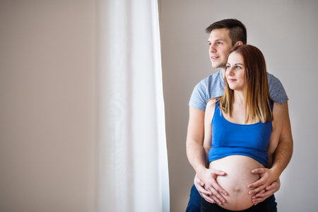 Pregnant woman and her partner, touching her belly.の写真素材